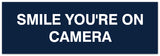 Signs ByLITA Basic Smile you're on camera Sign - Laser-Engraved Lettering | Durable ABS Plastic | Vibrant Colors | Powerful Foam Tape