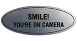 Signs ByLITA Oval Smile You're on Camera Sign - Laser-Engraved Lettering | Durable ABS Plastic | Vibrant Colors | Powerful Foam Tape